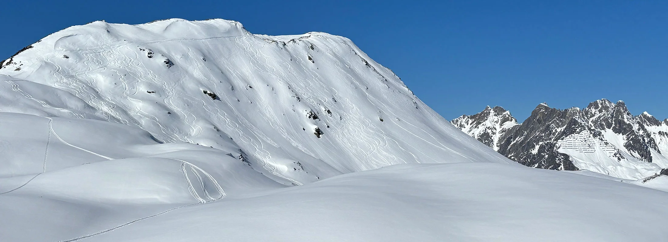 Verschneiter Berghang mit Skitourenspuren im Hochgebirge