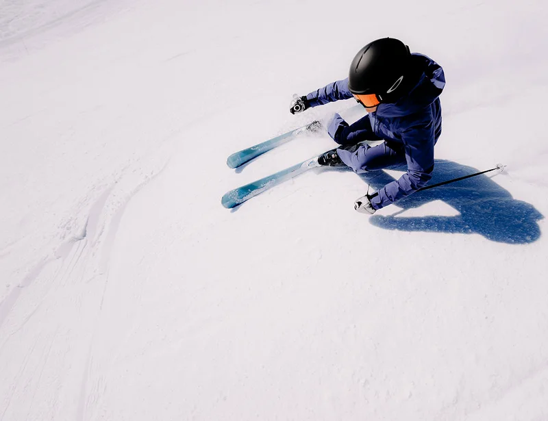Skifahrerin in tiefer Kurvenlage aus der Vogelperspektive – Skitechnik und Carving