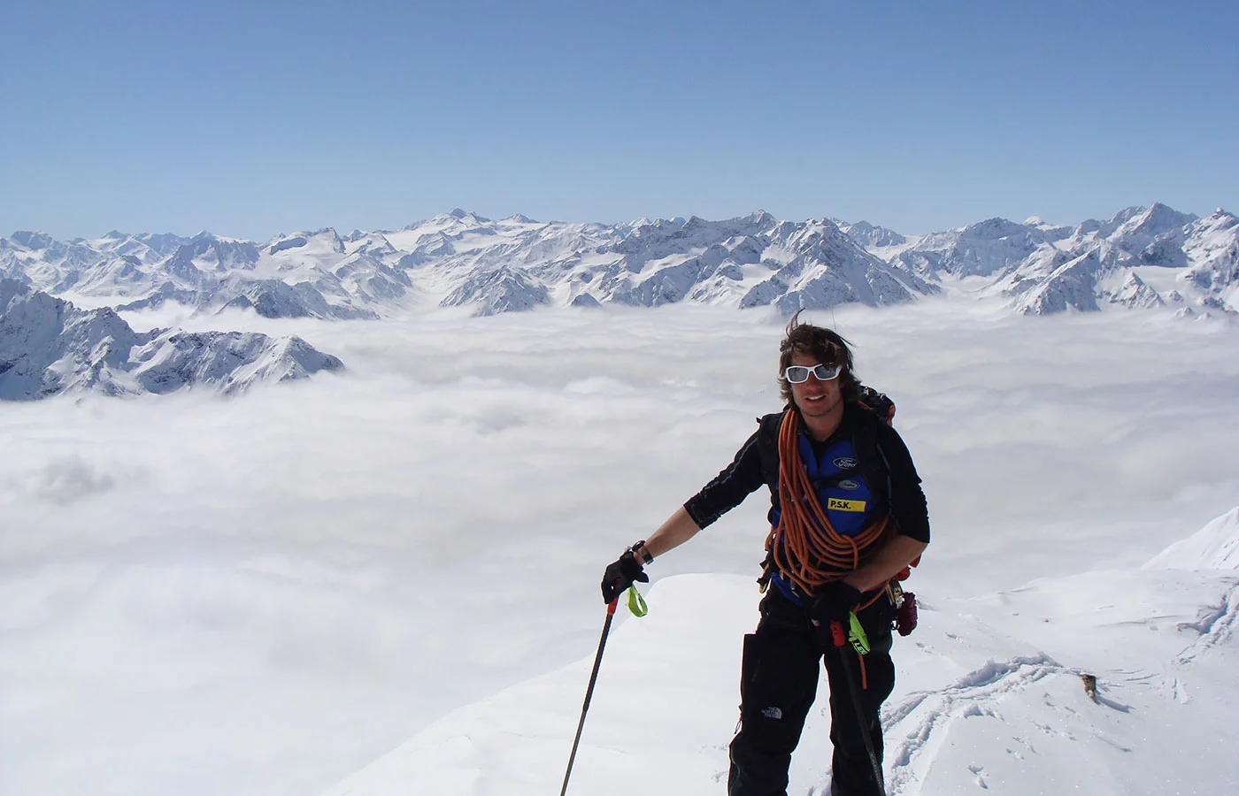 Bergführer mit Seil vor einem Nebelmeer und Alpenpanorama
