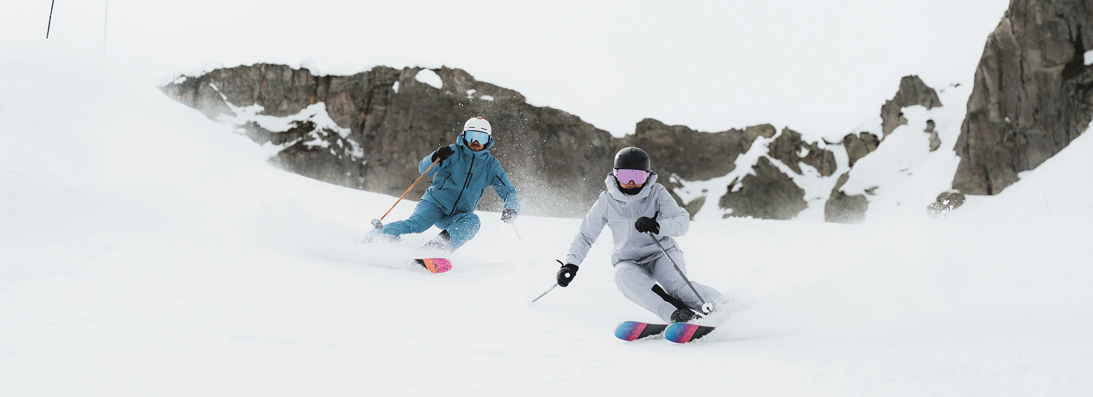 Zwei Skifahrerinnen beim Carving unter Felsen – Ski Performance Coaching