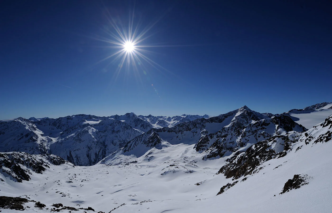 Sonne über dem Gletscher und verschneiten Gipfeln im Hochgebirge