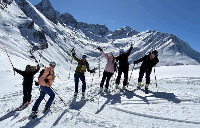 Gruppe von Skitourengehern jubelt im sonnigen Hochgebirge