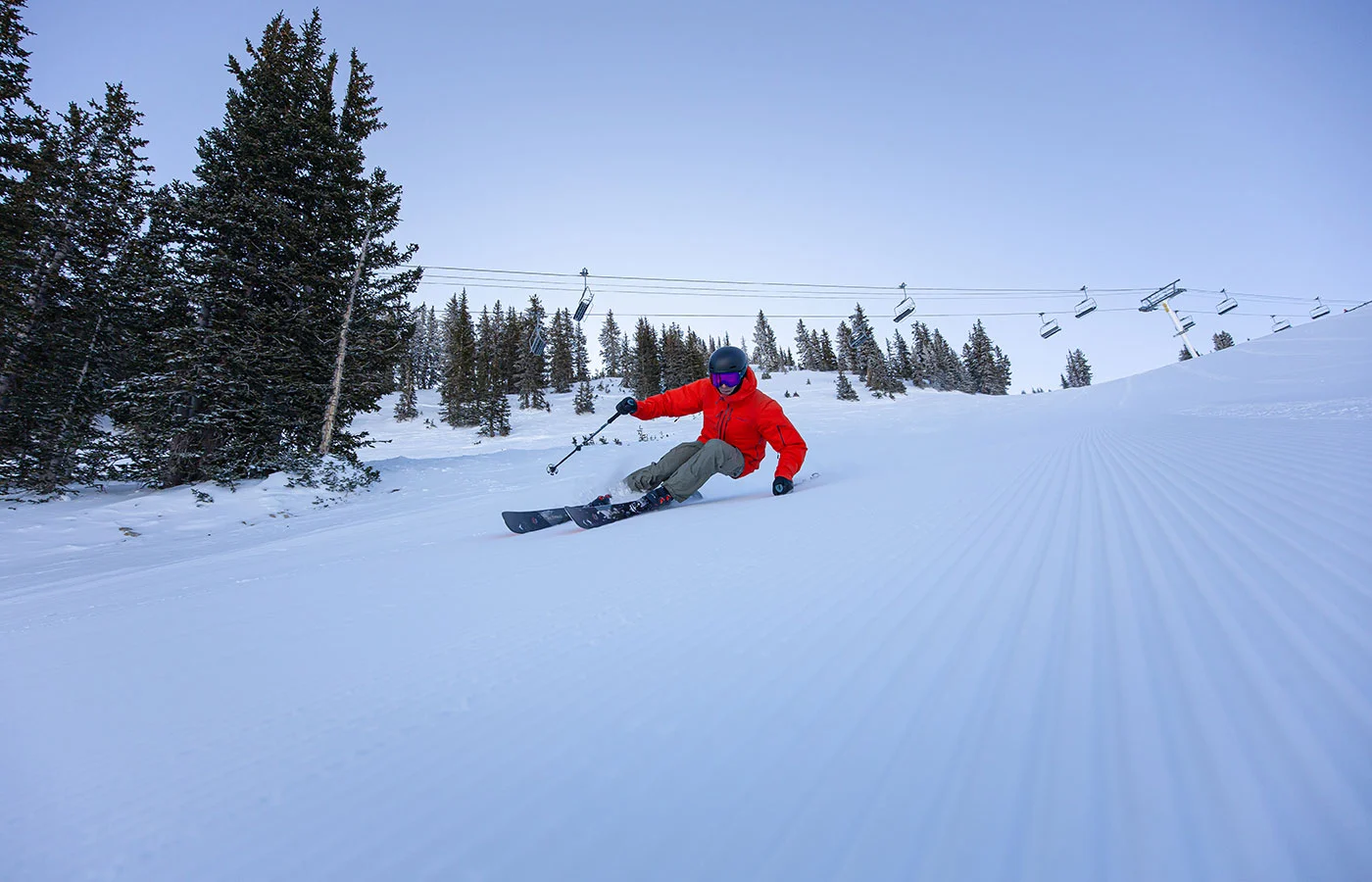 Skifahrer in tiefer Kurvenlage beim Carving vor dem Sessellift