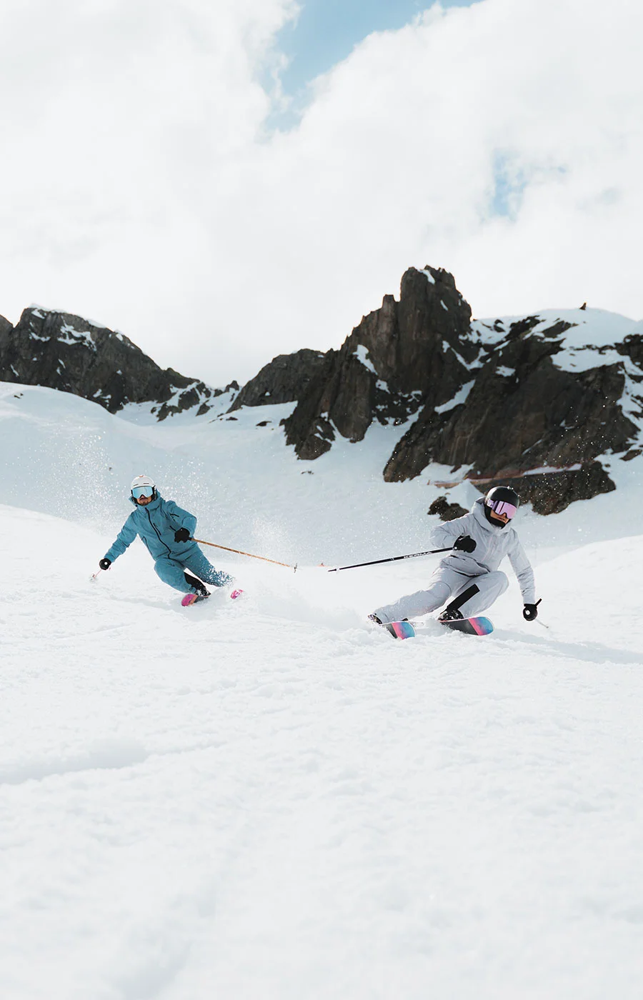 Skifahrerinnen bei der Abfahrt unter markanten Felsgipfeln